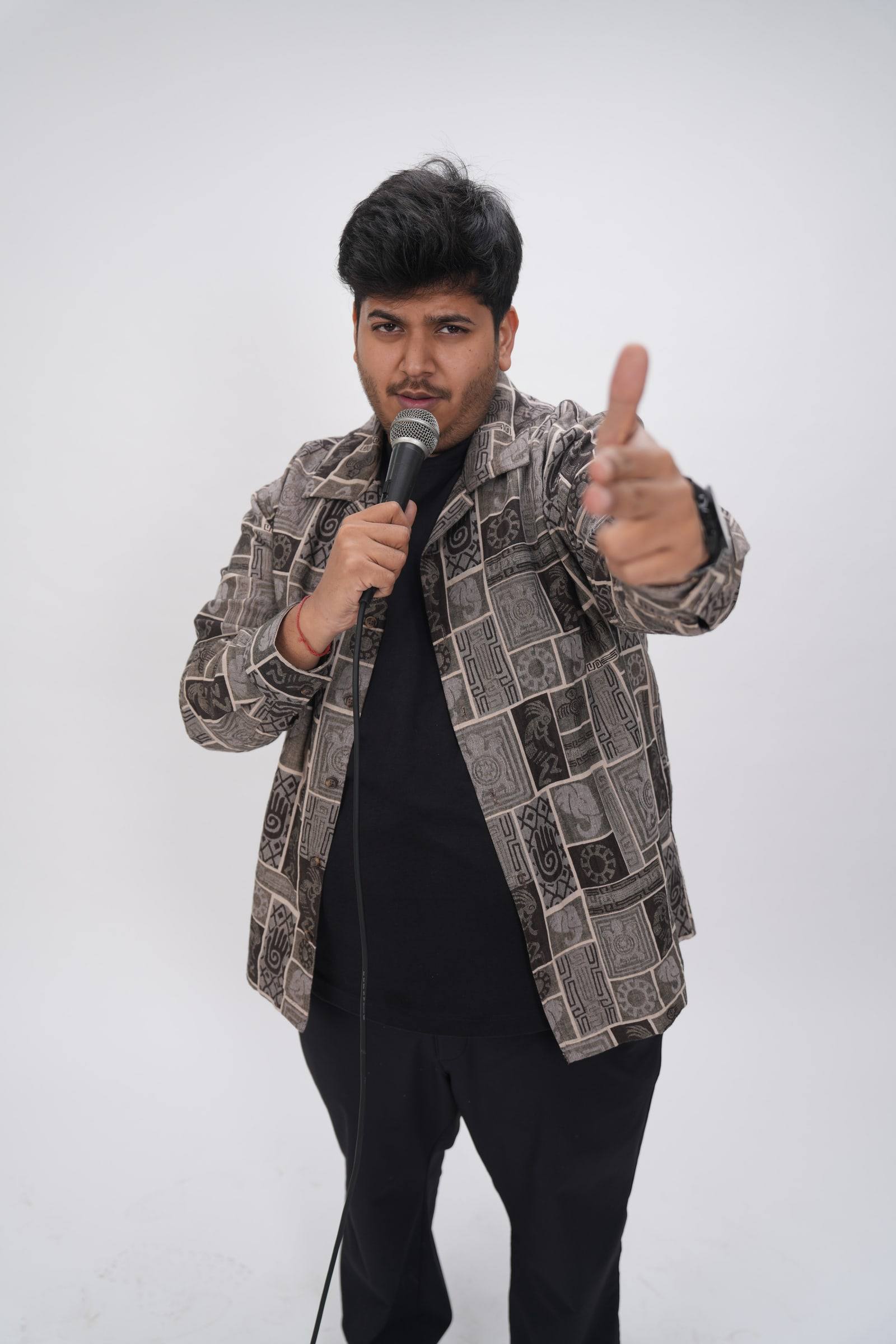 Kaustubh Agarwal pointing at the camera with a microphone in his other hand